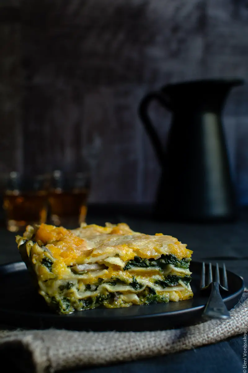 Cottage Cheese Vegetable Lasagne with Butternut Squash, Spinach and Mushrooms www.thefoodiecorner.gr Photo description: Another side shot of the cut piece of lasagna, from a slightly bigger distance. There is a fork lying on the plate next to it.
