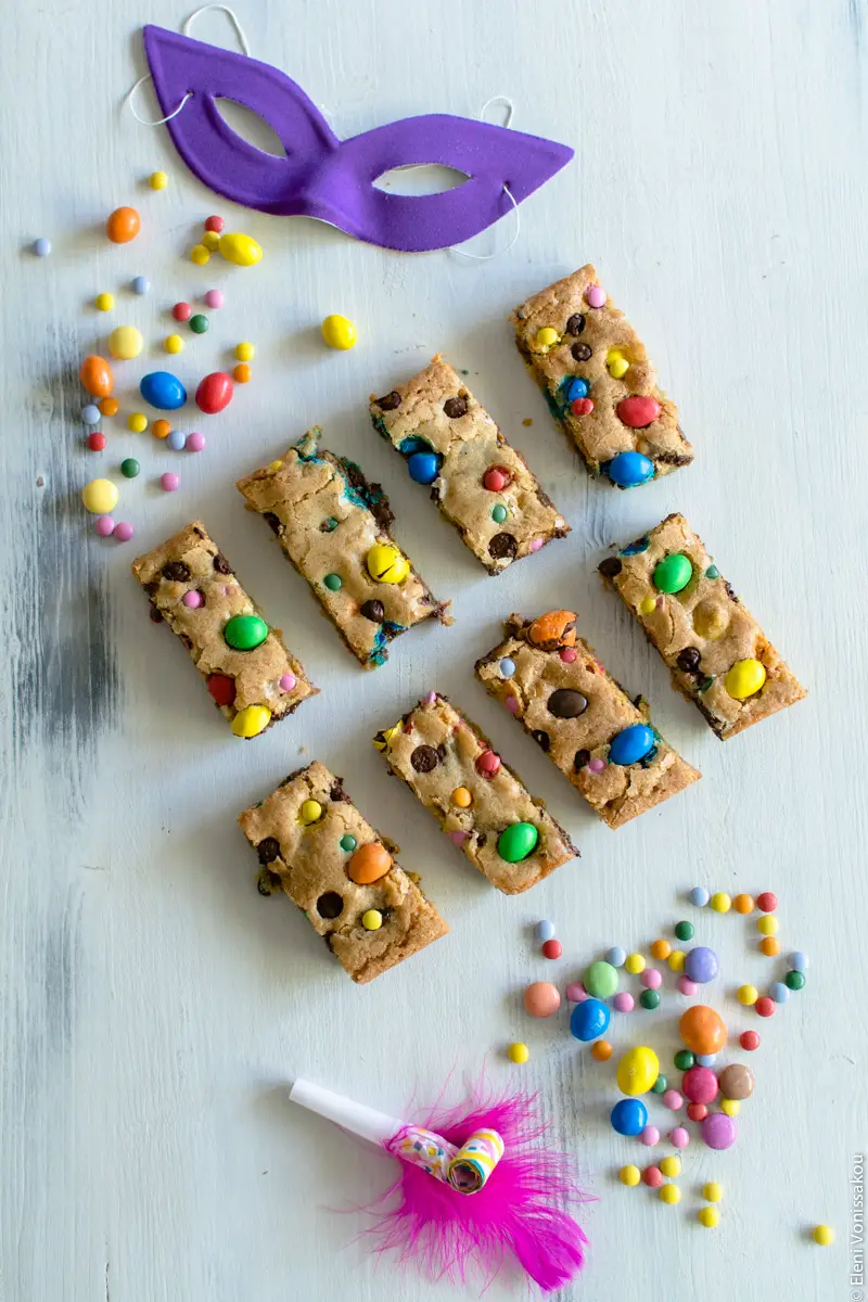 Easy, One-bowl, Colourful Chocolate Chip Cookie Bars www.thefoodiecorner.gr Photo description: Same set up as main photo, but instead of white feathers at the bottom of the photo is a small party horn with a pink feather attached to it.