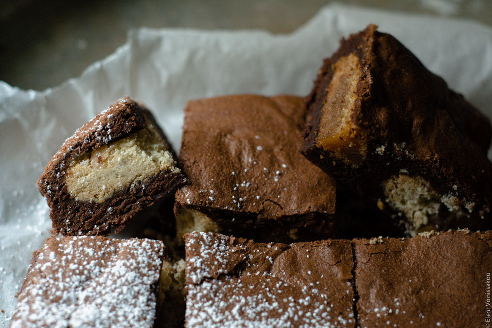 Brownies with Melomakarona and Kourabiedes - Aka Greek Christmas Brownies www.thefoodiecorner.gr Close up of the brownies on the baking paper, two of them turned sideways to reveal the inside treats, a kourabie and a melomakarono cut in half when the brownie was cut.