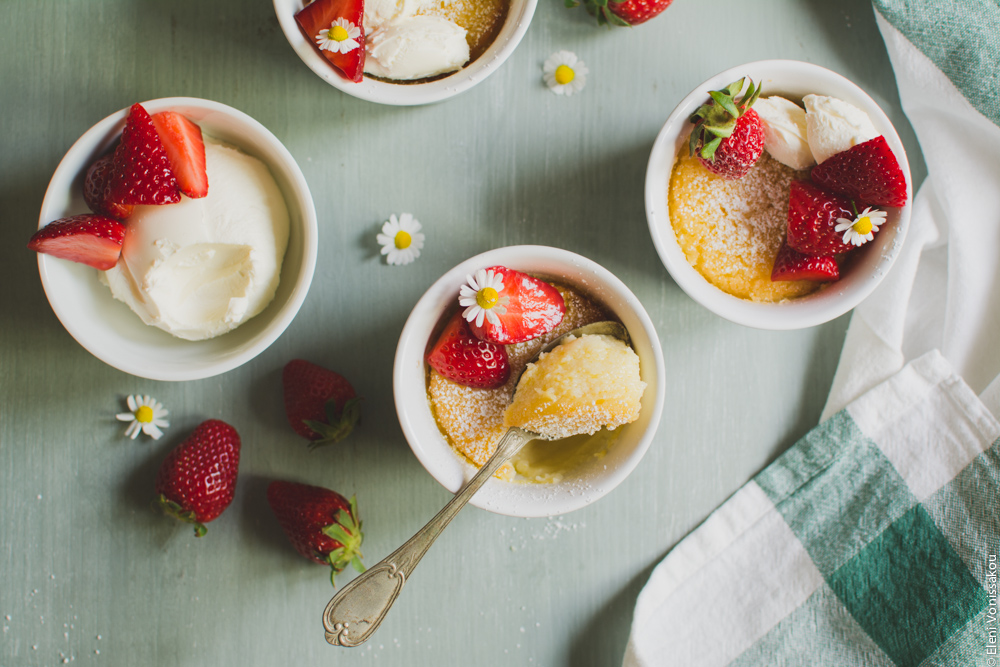 Easy Baked Lemon Puddings www.thefoodiecorner.gr Photo description: Two decorated puddings and the bowl of mascarpone sitting horizontally across the photo. The centre ramekin has a spoon with some pudding perched on top of it. 