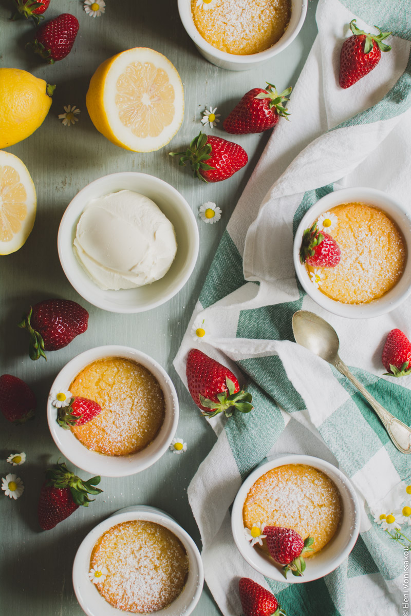 Easy Baked Lemon Puddings www.thefoodiecorner.gr Photo description: The lemon puddings with only a little sugar on top and a strawberry on three of them. Set up is the same as previous, but the camera is a little closer.