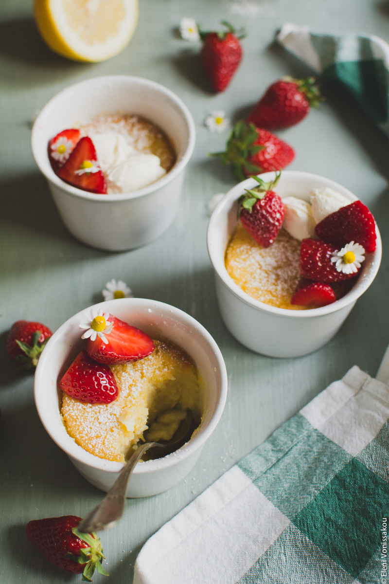 Easy Baked Lemon Puddings www.thefoodiecorner.gr Photo description: A close up ¾ view of three decorated puddings. The one in front has a spoon in it, and a piece of pudding missing.