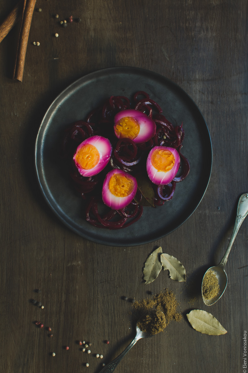 Beetroot Pickled Eggs www.thefoodiecorner.gr Photo description: The black plate with the beetroot noodles and the pickled eggs on top. Towards the bottom of the photo, the bay leaves and spices. In the top left corner are the cinnamon sticks, barely visible.