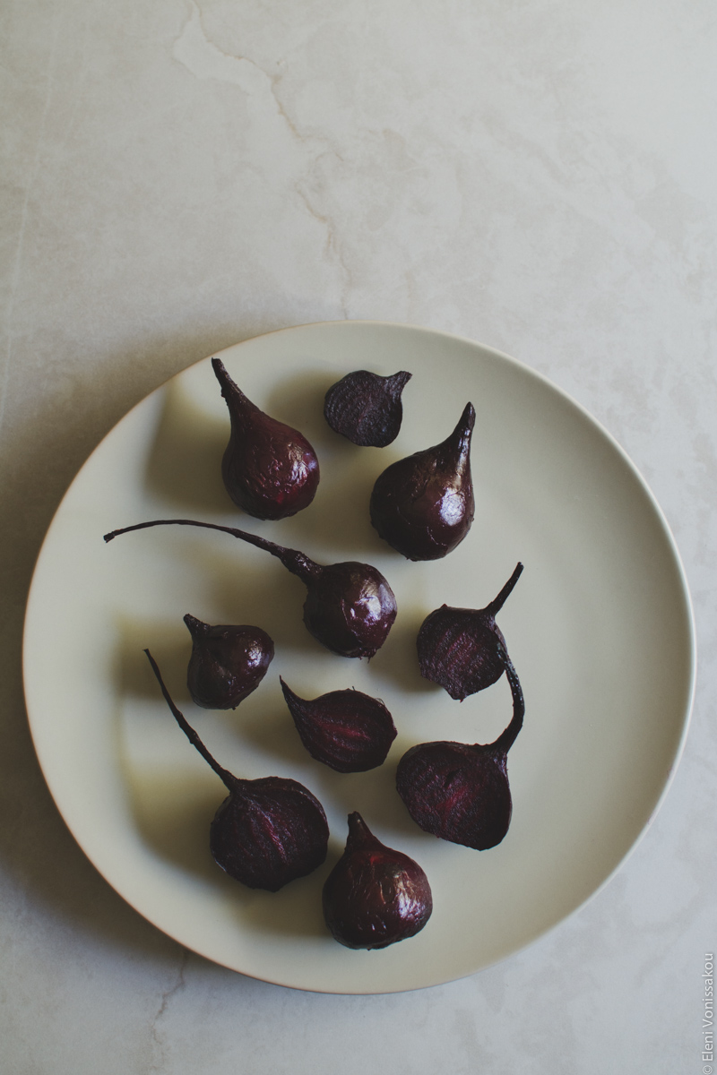 Roast Beetroot and Feta Pasta Salad with Greek Yoghurt and Cumin Dressing www.thefoodiecorner.gr Photo description: Roasted beetroot on a beige plate, on a light coloured surface. Most beetroot are whole, with some of them cut in half. They are arranged with their «tails» facing the top side of the photo.