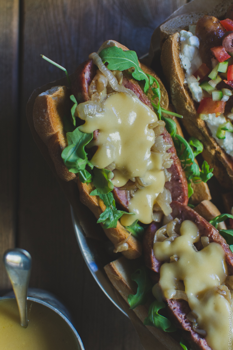 Two Ways with Greek Sausage Hot Dogs www.thefoodiecorner.gr - Photo description: A closer view of one of the hot dogs, with rocket, caramelised onions and beer cheese sauce on top.