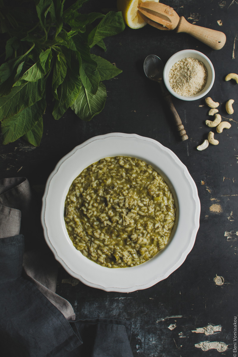 Vegan Ριζότο με Βλίτα και Μυρωδικά www.thefoodiecorner.gr Photo description: The plate of risotto without the vegan cheese on top. In the top right corner is the small bowl of «cheese» and a wooden lemon juicer sitting proped against half a squeezed lemon. 