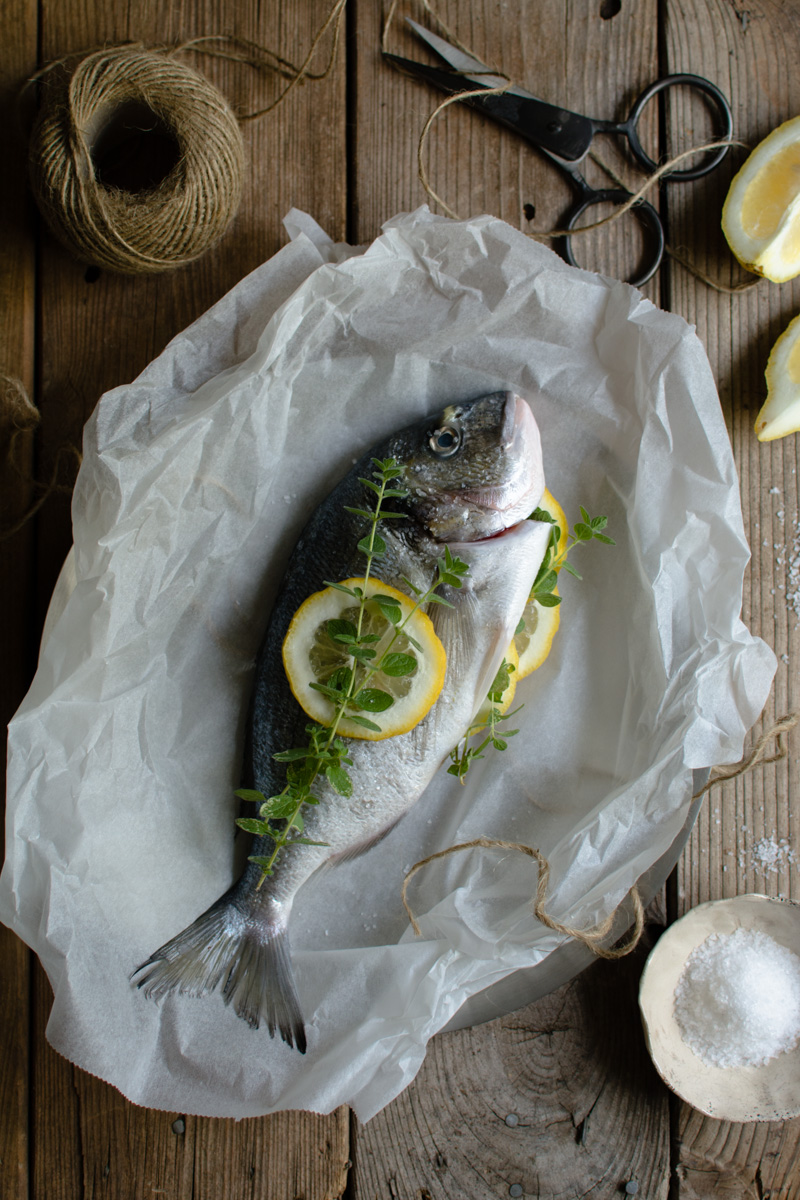 Gilt Head Bream (Dorade) – How to cook a whole fish in the slow cooker www.thefoodiecorner.gr Photo description: Same as previous photo, only a further away view of the fish prepped for cooking. Around it are a ball of string, some vintage scissors, some lemon wedges and a small ceramic bowl of coarse salt.