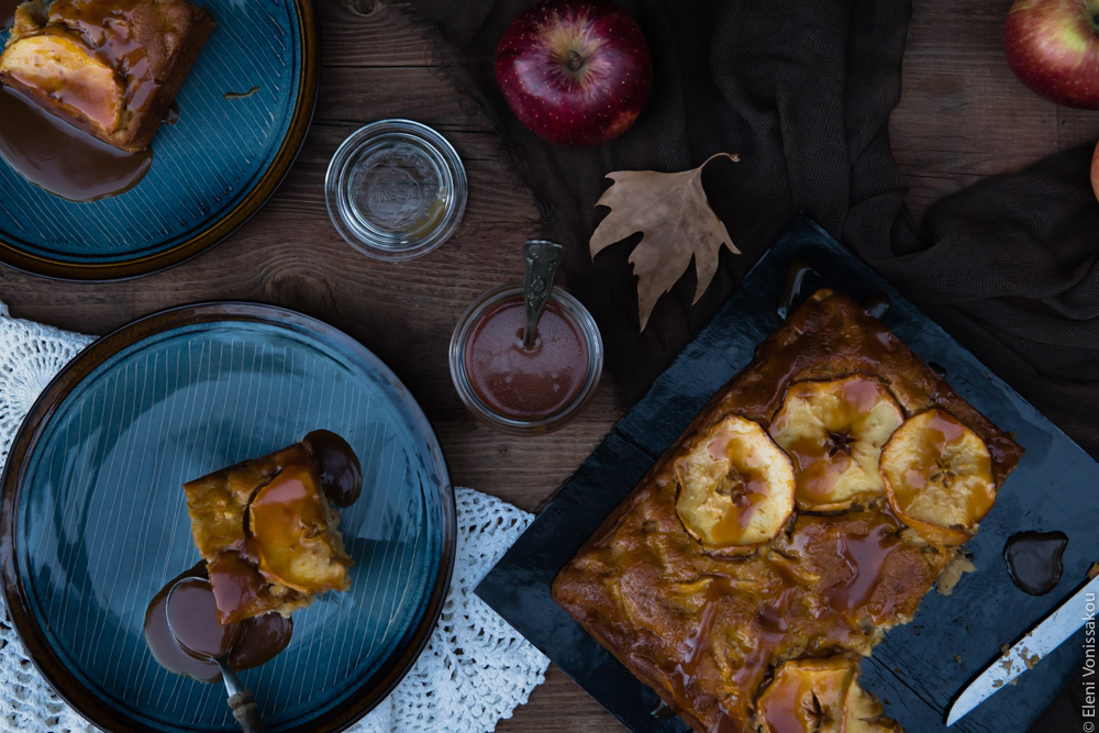 Easy, No Mixer Apple Cake with Salted Caramel Sauce www.thefoodiecorner.gr Photo description: Top view of the cut cake on the wooden table. Next to it are two plates with cake on and the jar of caramel.