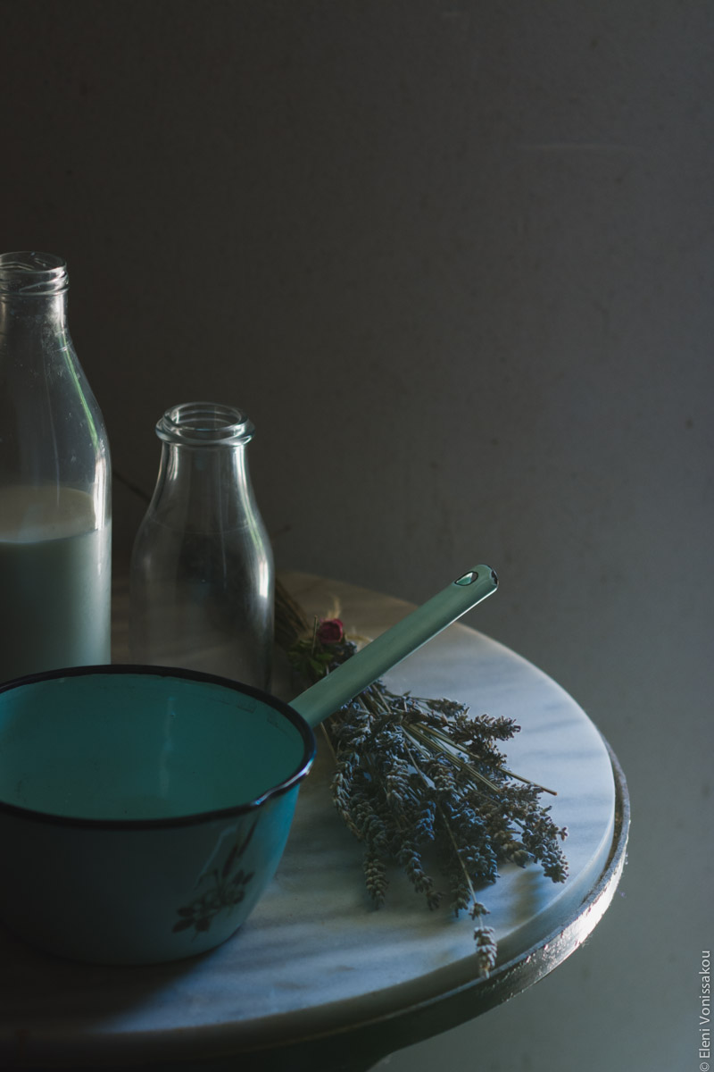 Capturing Athens Food Styling and Photography Workshop www.thefoodiecorner.gr Photo description: A tin saucepan sitting on a marble table. Next to it are a couple of milk bottles (some milk visible in one of them) and a bunch of dried lavender. The table is in a dark setting with some light coming in from the side.