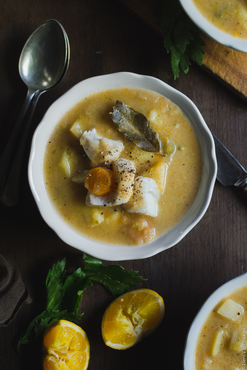 Orange and Lemon Fish Soup with Cod. My version of Greek Psarosoupa. www.thefoodiecorner.gr Photo description: A closer top view of one of the bowls of soup with all the veggies and fish in the centre. Two squeezed pieces of orange lie towards the bottom of the picture.