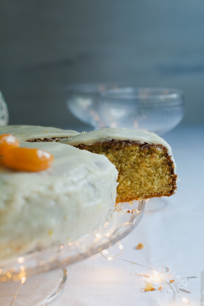 Greek New Year’s Cake (Vassilopita) with Mandarin, Almonds and Cardamom www.thefoodiecorner.gr Photo description: Side view of the cake with a slice having been cut and pulled out part of the way, revealing some of the inside of the cake.