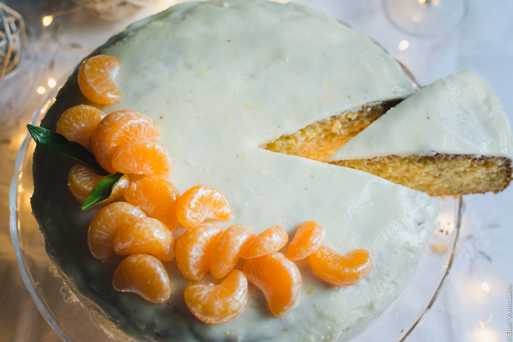 Greek New Year’s Cake (Vassilopita) with Mandarin, Almonds and Cardamom www.thefoodiecorner.gr Photo description: Top view of the cake with a slice having been cut and pulled out part of the way, revealing some of the inside of the cake.