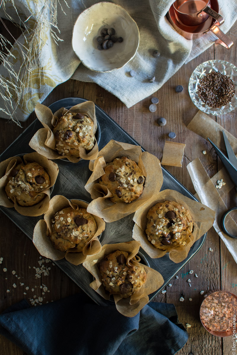 Healthy Banana Muffins with Oats, Tahini, Honey and Chocolate Chips www.thefoodiecorner.gr Photo description: The muffin tin just out of the oven, with the baked muffins still inside. In the top right corner some of the almost empty bowls and in the bottom left corner a dark linen napkin.