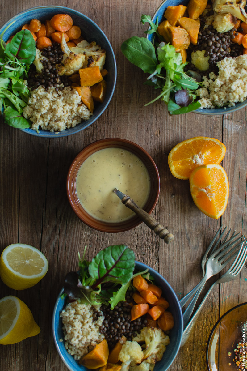 Lenten Bowls with Bulgur Wheat, Beluga Lentils, Roast Veggies and Honey Tahini Dressing www.thefoodiecorner.gr Photo description: Three filled bowls arranged around the small bowl of dressing. Between them some orange and lemon wedges.