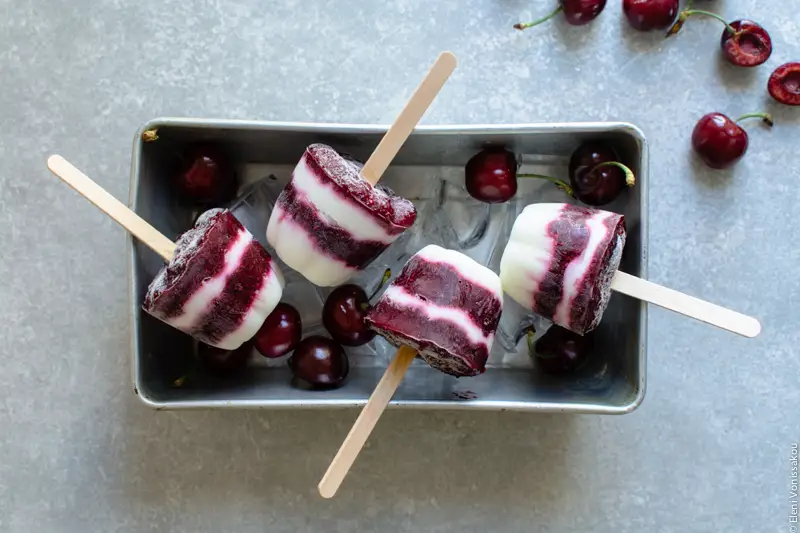 Frozen Cherry Treats – 3 Ways www.thefoodiecorner.gr Photo description: Four muffin shaped popsicles lying on some giant ice cubes in a metal loaf pan.