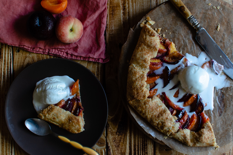 Easy Anthotyro Galette with Spiced Summer Fruit www.thefoodiecorner.gr Photo description: A closer view of the almost finished galette, the melting ice cream and one of the plates to its left. The plate has a piece of galette and some ice cream on it. Towards the top of the photo a peach, a plum with condensation on it, and an apricot half barely visible. The fruit is sitting on a linen napkin.