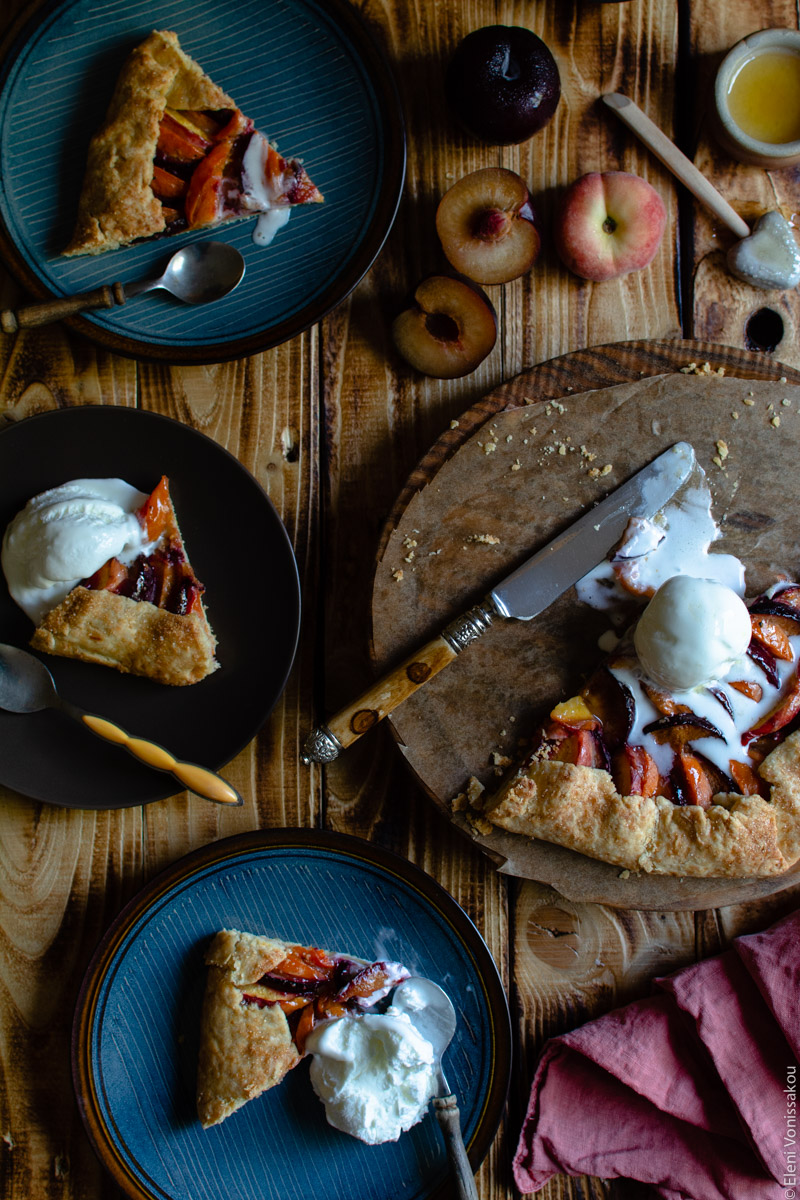 Easy Anthotyro Galette with Spiced Summer Fruit www.thefoodiecorner.gr Photo description: To the right the cutting board with the galette, now almonst gone. The ice cream is melting onto the baking paper underneath. To the left of the photo three plates with pieces of galette and spoons on them. Two have scoops of vanilla ice cream.