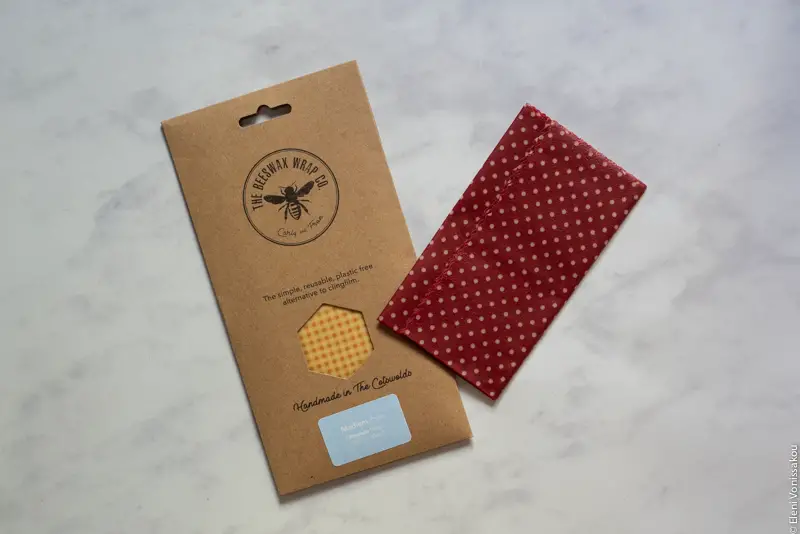 A packet of beeswax wraps and one wrap lying on a marble surface.
