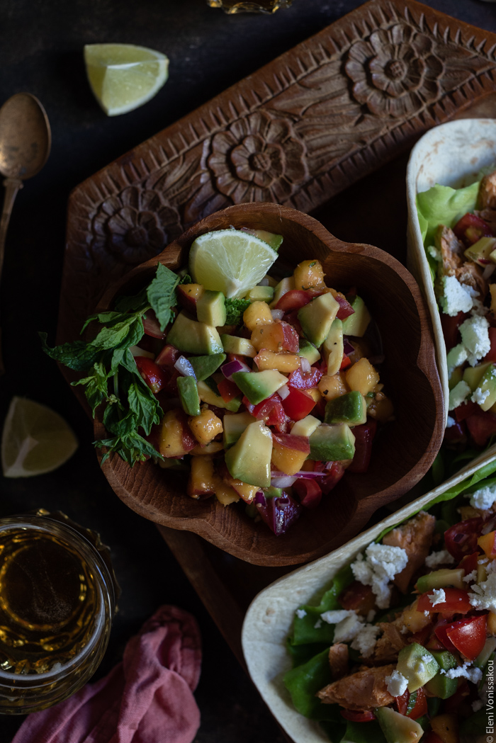 Spicy Salmon Tacos with Manouri Cheese and Peach Avocado Salsa www.thefoodiecorner.gr Photo description: A close up of a small wooden bowl filled with salsa. The bowl is on a wooden tray.