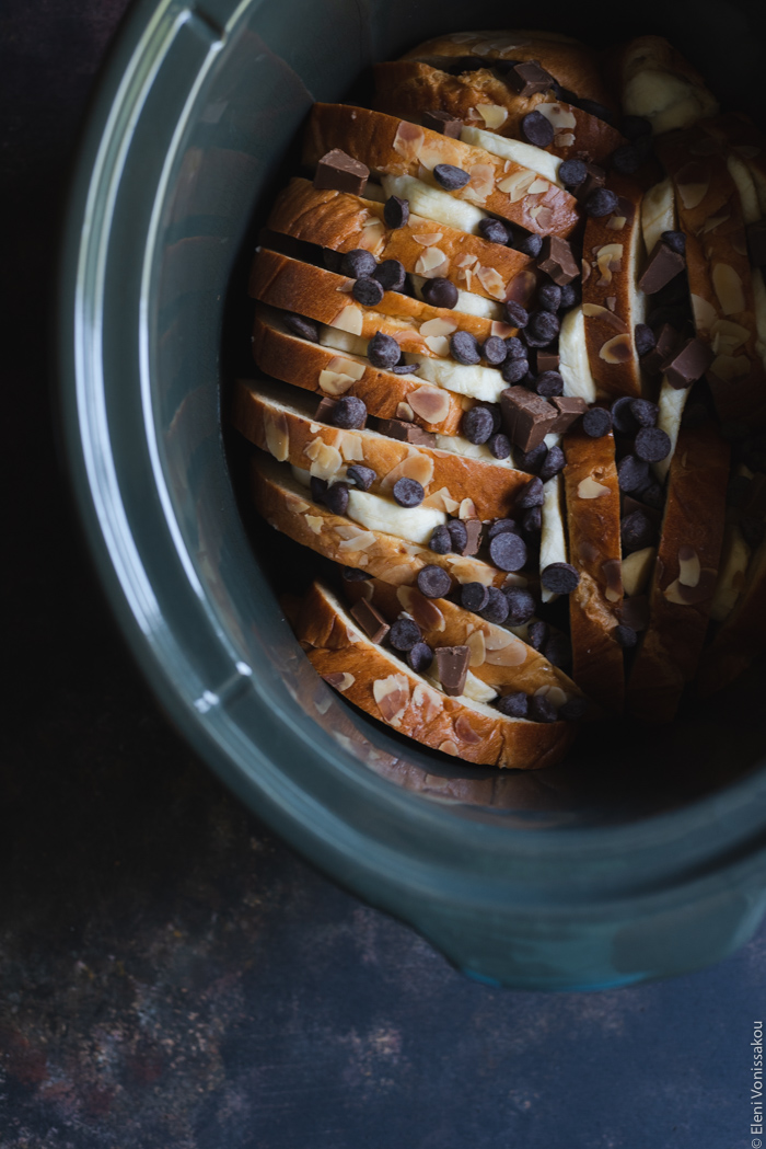 Slow Cooker Sweet-Bread Pudding with Banana, Peanut Butter and Chocolate Chips www.thefoodiecorner.gr Photo description: The slow cooker insert with the slices of tsoureki, the pieces of banana among them, and the chocolate chips scattered on top.