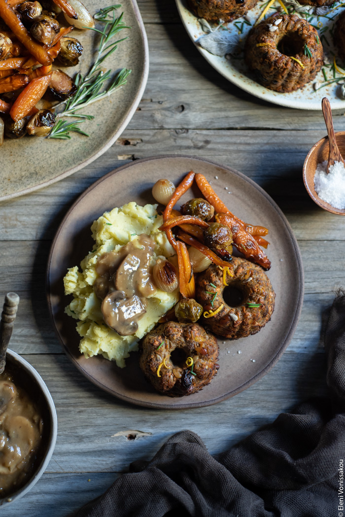 Festive Sweet Potato, Mushroom and Chestnut Mini Nut Loaves www.thefoodiecorner.gr Photo description: A ceramic plate filled with festive food. Mashed potatoes, roasted vegetables (Brussels sprouts and carrots) and muffin-shaped nut loaves smothered in mushroom gravy.