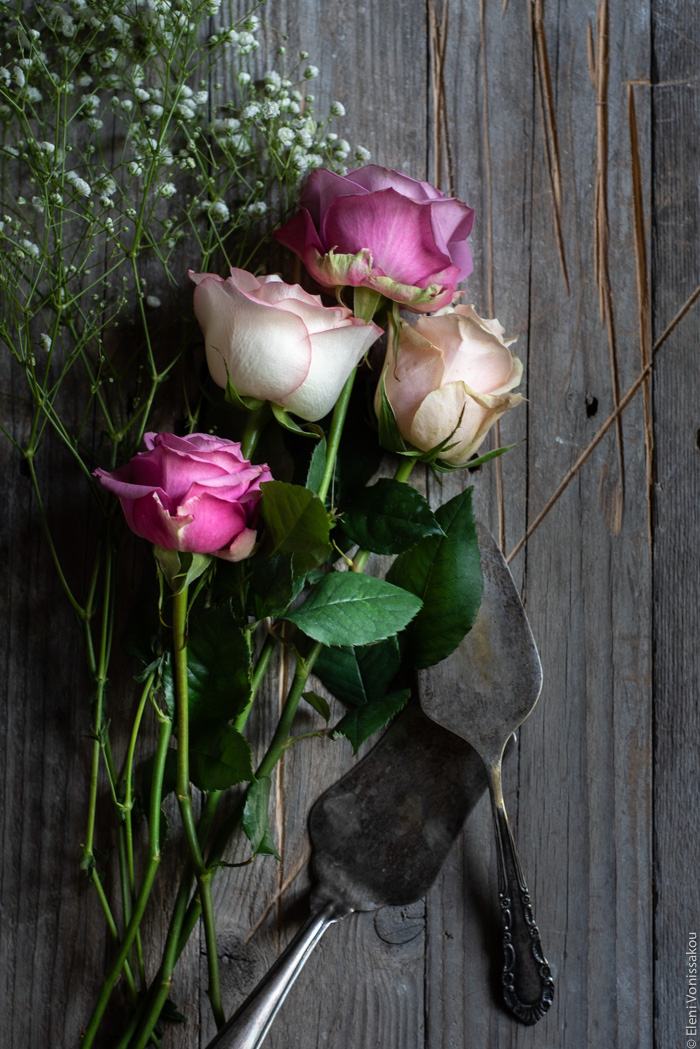 Almond Cardamom Rose Cake with Semolina and Olive Oil www.thefoodiecorner.gr Photo description: a small bunch of roses on a wooden surface. Next to them are two vintage cake servers.