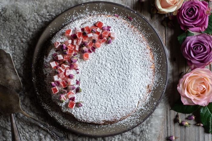 Almond Cardamom Rose Cake with Semolina and Olive Oil www.thefoodiecorner.gr Photo description: The cake with the cut roses next to it. To the left of the plate are the cake servers.