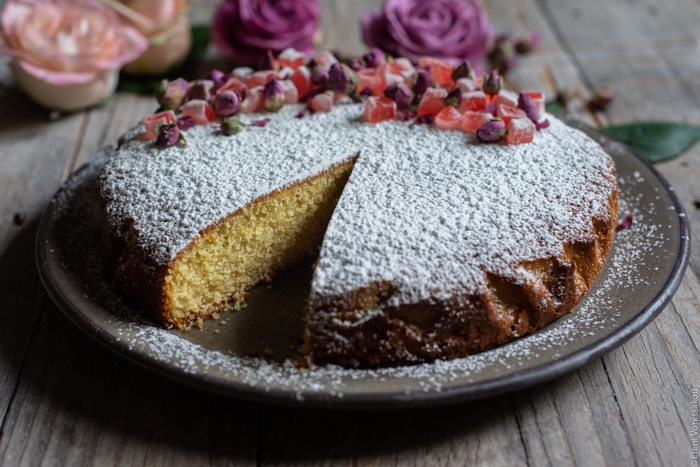 Almond Cardamom Rose Cake with Semolina and Olive Oil www.thefoodiecorner.gr Photo description: A side view of the cake. A slice has been cut so the inside of the cake is visible.