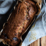 Chocolate Chip Emmer Flour Banana Bread with Tahini www.thefoodiecorner.gr Photo description: An overhead view of the banana bread loaf in the baking tin, lined with grease proof paper. The tin is sitting on a couple of bunched up tea towels.