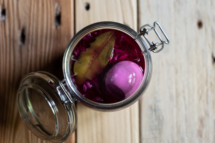 Quick Pickled Eggs and Red Cabbage www.thefoodiecorner.gr Photo description: An overhead view of an open jar with pickling liquid inside. Just visible on the surface is an egg and a bay leaf.