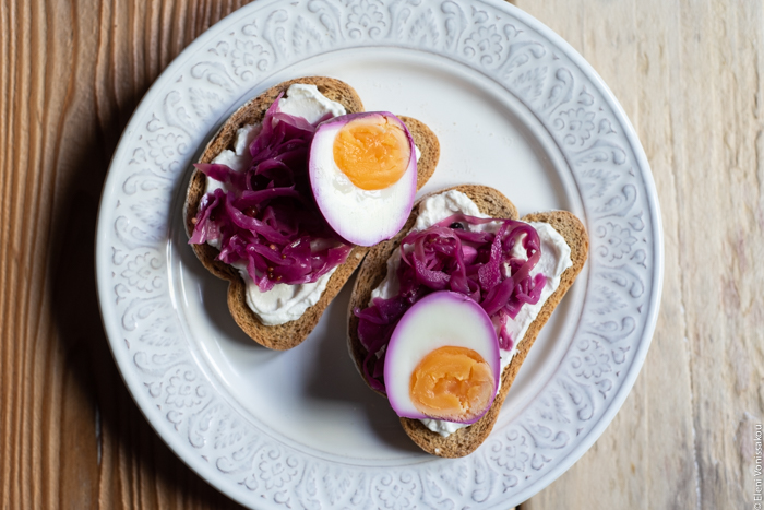 Quick Pickled Eggs and Red Cabbage www.thefoodiecorner.gr Photo description: A plate with two wheat rusks topped with soft white cheese, pickled cabbage and pickled egg halves.