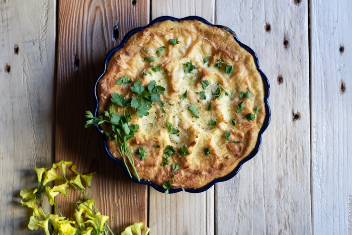 Shepherd’s Pie. To use up those Easter lamb leftovers. www.thefoodiecorner.gr Photo description: An overhead view of a shepherd’s pie with some parsley decorating the top. To the left of the dish are some yellow spring flowers. Everything is on a wooden surface consisting of slightly different coloured planks.