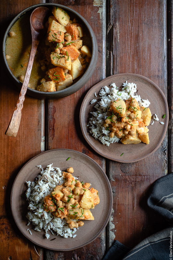 Slow Cooker Sweet Potato Chickpea Coconut Curry www.thefoodiecorner.gr Photo description: A top view of two ceramic plates with basmati and wild rice, and curry on top. In the top left corner of the photo is a large ceramic serving bowl with curry and a wooden serving spoon inside.