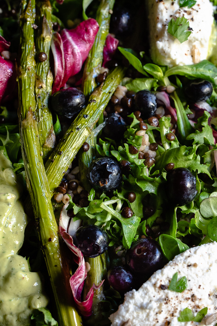 Green Salad with Buckwheat, Beluga Lentils, Roasted Asparagus and Avocado Dressing www.thefoodiecorner.gr Photo description: a very close view of a salad consisting of mixed salad leaves, asparagus, beluga lentils, buckwheat and blueberries. Some soft white cheese and some salad dressing are half visible to the side of the image.