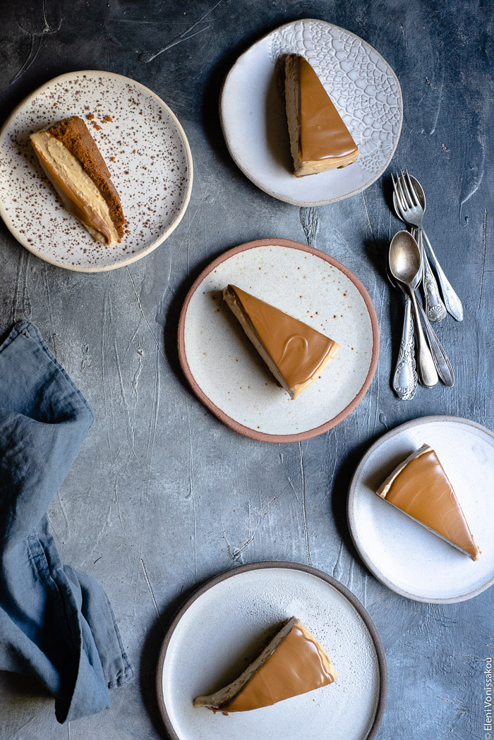 Εύκολο Τσίζκεϊκ με Άλειμμα Μπισκότου Speculoos (Χωρίς Ψήσιμο) www.thefoodiecorner.gr Photo description: five ceramic plates each with a slice of cheesecake. Some spoons to the right of the image and a linen tea towel to the left, half visible.