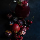 Pomegranate and Sour Cherry Rosé Sangria www.thefoodiecorner.gr Photo description: A jug of sangria with some oversized ice cubes, cherries and mint to garnish. In front of the jug are lots of red fruits (a cut pomegranate, cherries, plums and raspberries).