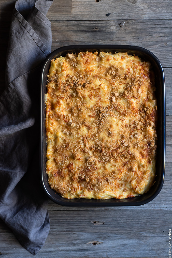 Broccoli Cheese Pasta Bake www.thefoodiecorner.gr Photo description: A baking dish full of cooked golden broccoli pasta bake. Next to it is a bunched up linen napkin.