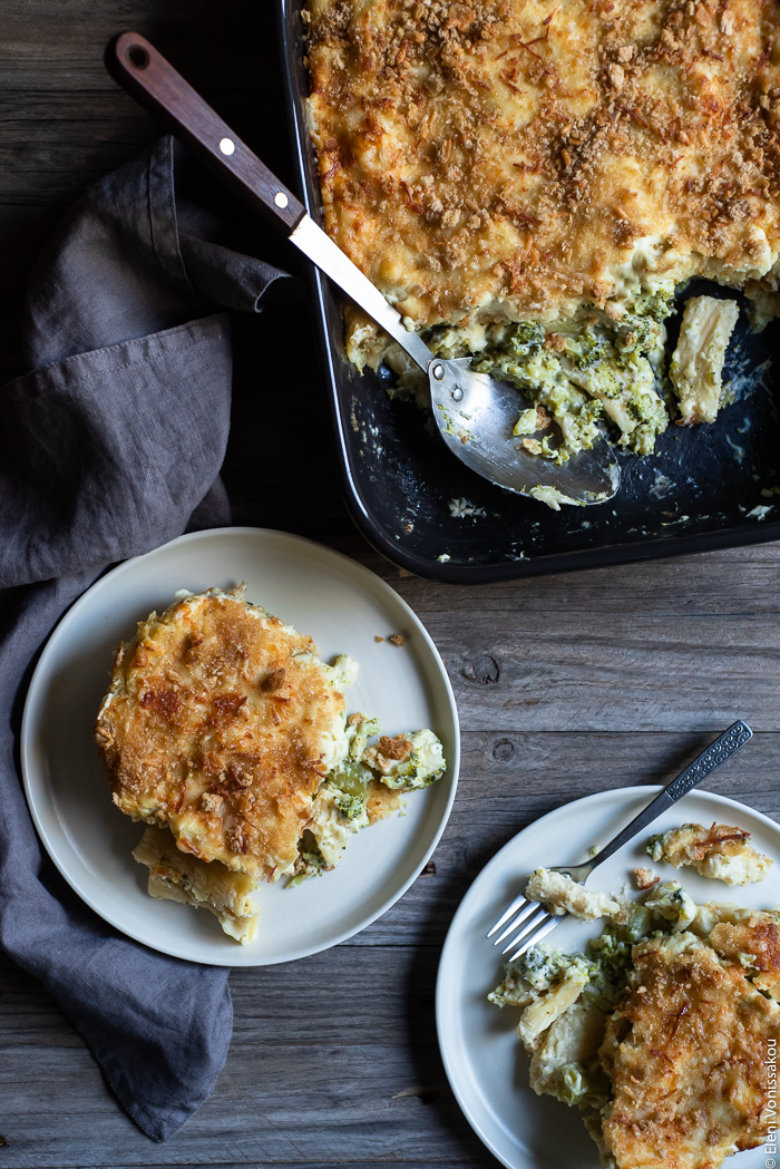 Broccoli Cheese Pasta Bake www.thefoodiecorner.gr Photo description: In the top right corner is a baking dish with cooked broccoli pasta bake, a few pieces of which are missing. A large serving spoon rests in the dish. To the bottom of the dish are two plates each with a piece of pasta bake on it. 