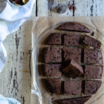 Plant-Based, Date-Sweetened Chocolate Banana Oat Cake-Bars, in the Slow Cooker www.thefoodiecorner.gr Photo description: Chocolate Banana Oat Cake-Bars cut up and arranged (in the shape of the slow cooker) on a piece of grease-proof paper on a wire rack. To the top is a small bowl with cocoa powder, to the left of the photo is a bowl of dates, chocolate and banana chips on a linen napkin. To the bottom left are some small coffee cups.