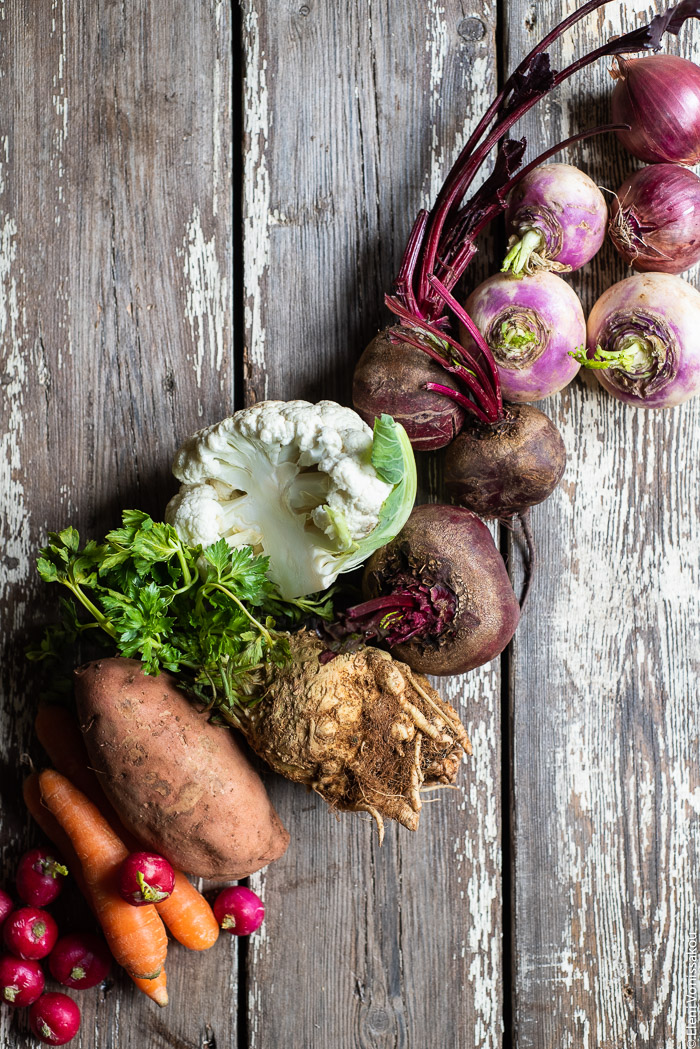 Cumin Roasted Root Vegetable Medley. My Winter “Briam”. www.thefoodiecorner.gr Photo description: Winter vegetables arranged in a row on a worn wooden surface. Radishes, carrots, sweet potato, celery root, cauliflower, beetroot, turnips and onions.