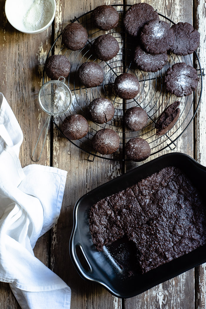 Chocolate Tahini Olive Oil Cookies or Brownies (One Recipe, Two Treats) www.thefoodiecorner.gr Photo description: A cooling rack with cookies on it and a baking dish with brownies, one of them missing. To the side of the dish lies a linen napkin. Everything is on a distressed wooden surface.