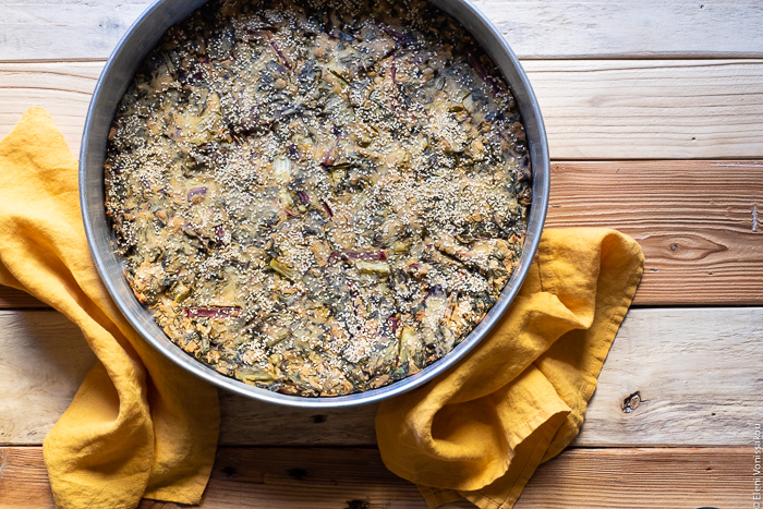 Easy Greek “Flour Pie” with Cornmeal, Spelt and Mixed Greens (Spinach and Beets) www.thefoodiecorner.gr Photo description: A large tin containing a baked pie with greens. Around the sides of the tin are two linen napkins.