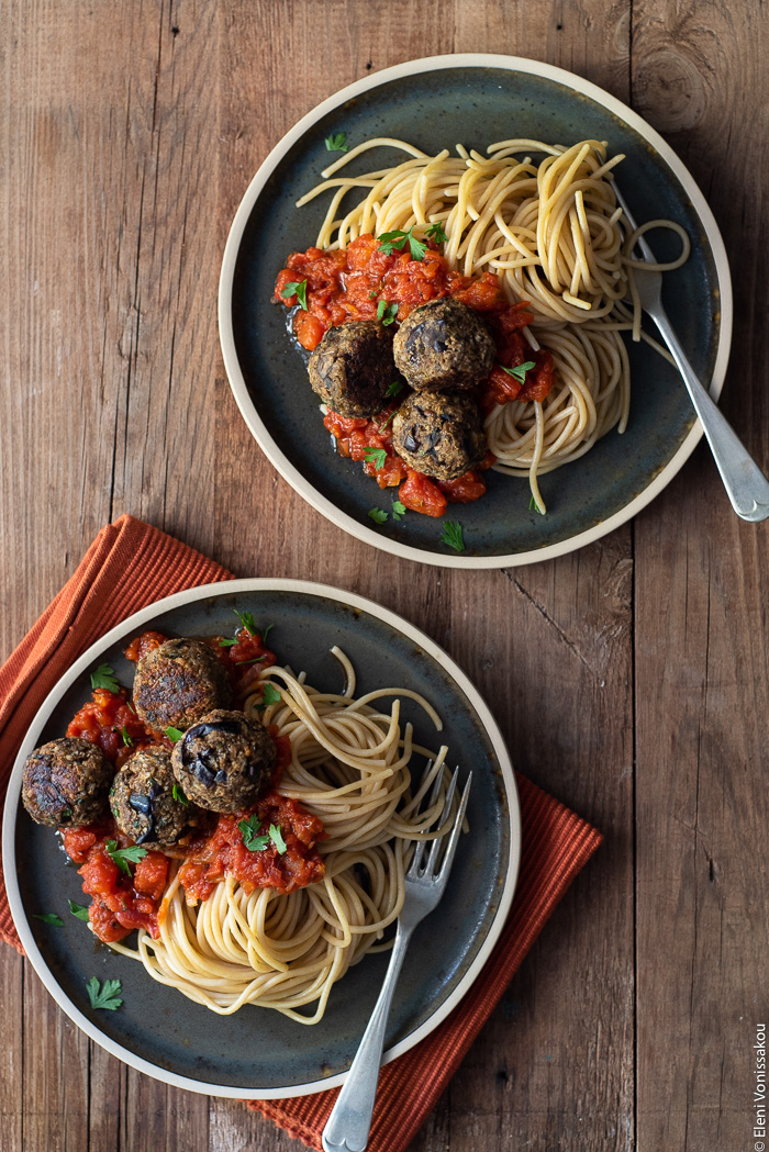 Aubergine (Eggplant) “Meatballs” with Tomato Sauce and Spaghetti www.thefoodiecorner.gr Photo description: Two plates of spaghetti and eggplant meatballs with tomato sauce. Each has a fork lying on the side. One plate is on a folded fabric place mat.