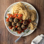 Aubergine (Eggplant) “Meatballs” with Tomato Sauce and Spaghetti www.thefoodiecorner.gr Photo description: A large ceramic plate full of spaghetti with sauce and aubergine meatballs on top. The plate is on a wooden surface. To the bottom is a bunched up linen napkin.