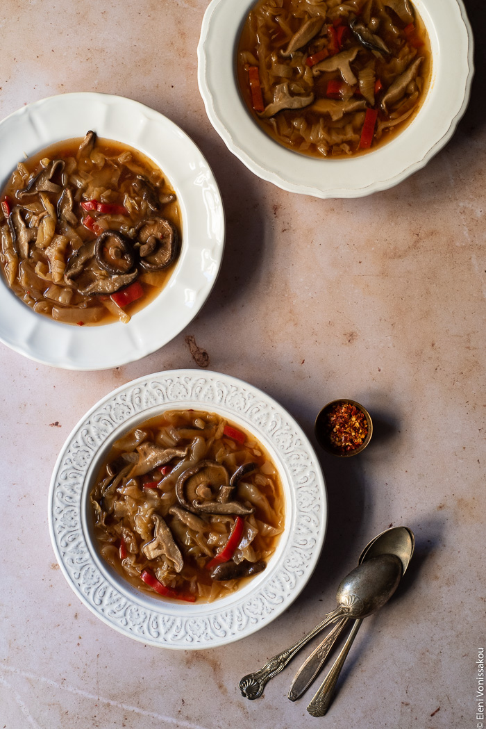 Slow Cooker Hot and Sour Cabbage Soup with Shiitake Mushrooms www.thefoodiecorner.gr Photo description: Three bowls of soup on a marble surface. Beside one of the bowls are three spoons.