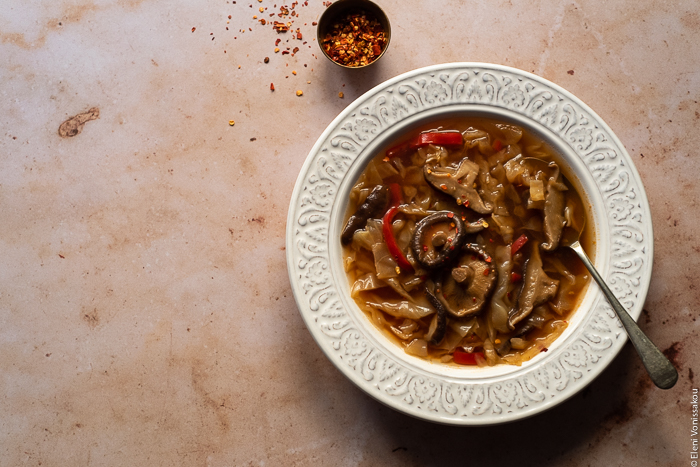 Slow Cooker Hot and Sour Cabbage Soup with Shiitake Mushrooms www.thefoodiecorner.gr Photo description: One bowl of soup on a marble surface. Visible inside the soup are the vegetables and a couple of whole mushrooms.