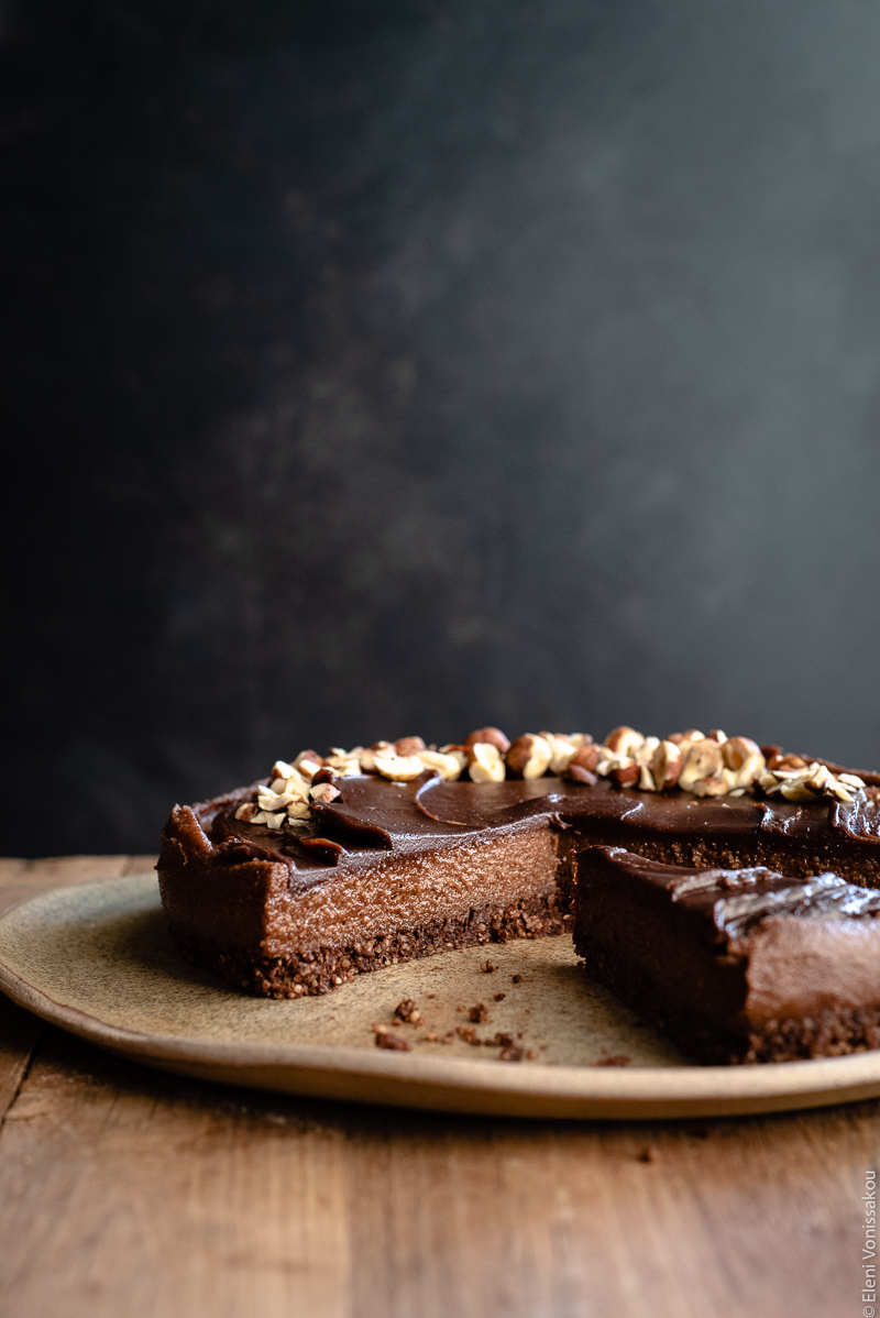 No Bake Cacao Peanut Butter Tart with a Hazelnut Base (Plant-Based) www.thefoodiecorner.gr Photo description: A side view of a cut chocolate tart showing the inside with its three layers, base, filling and topping.