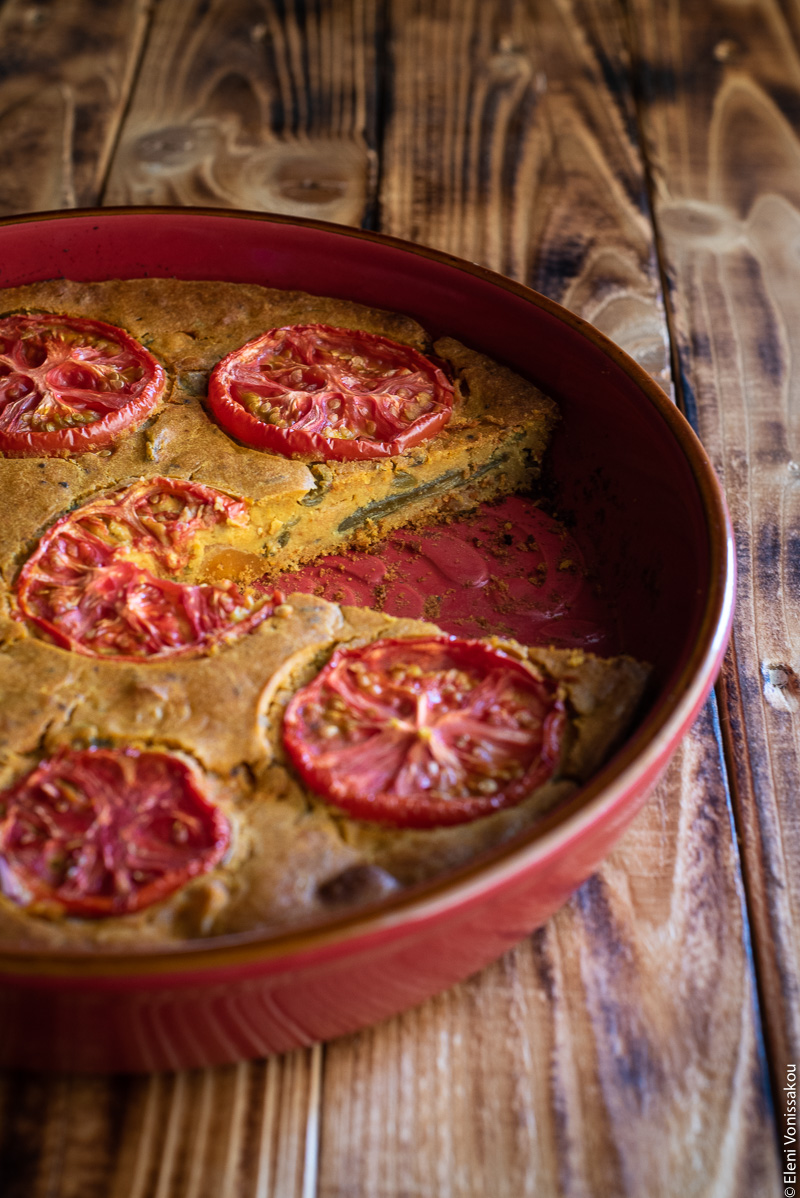 Chickpea Flour Pie (aka Plant-Based Frittata) with Leftover Green Bean Stew www.thefoodiecorner.gr Photo description: a red baking dish with a pretty pattern on the inside. A slice has been removed and there are some green beans barely visible from the side inside the pie.