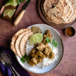 Sri Lankan Inspired Jackfruit Curry in the Slow Cooker www.thefoodiecorner.gr Photo description: A bowl of jackfruit curry on basmati rice, a few flatbreads at the side of the dish. To the top of the image a plate of more round flatbreads (roti). To the top left some chopped parsley and cut lime.