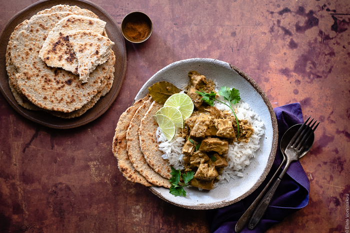 Sri Lankan Inspired Jackfruit Curry in the Slow Cooker www.thefoodiecorner.gr Photo description: A bowl of jackfruit curry on basmati rice, a few flatbreads at the side of the dish. To the left of the image a plate of more round flatbreads (roti). To the right of the dish a linen napkin and some vintage cutlery.